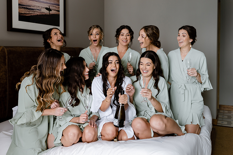 The bride and her bridesmaids having champagne before dressing up