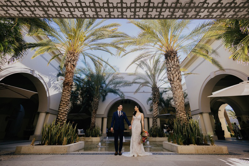 The couple standing by some palmtrees