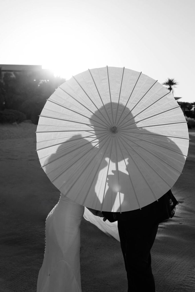 The newly weds kissing behind an umbrella