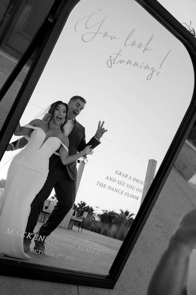 The couple posing in front of a mirror